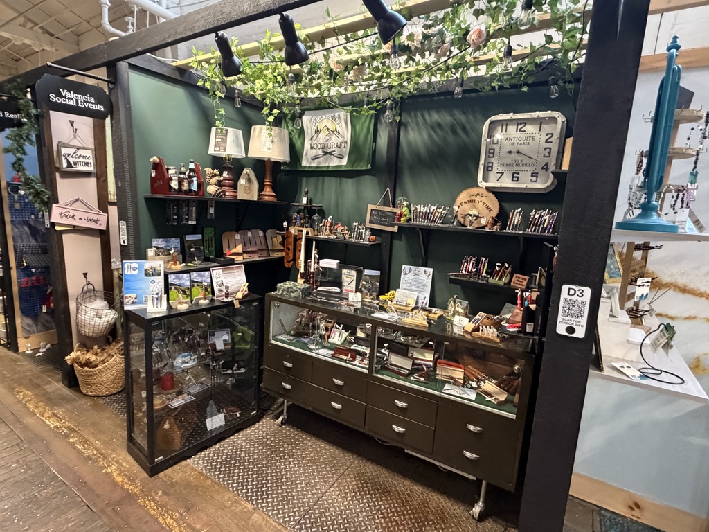 The Ratlum Mountain Woodcraft booth at Market Street Creatives, with dark green walls and black shelving full of handmade pens